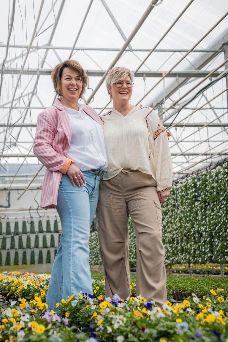 De twee eigenaressen van Label Trends tussen de voorjaarsbloemen in een kas