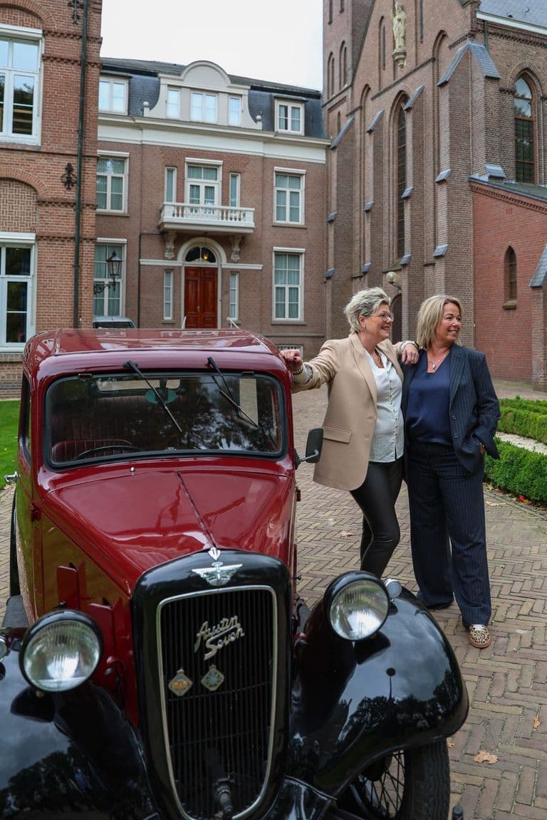 Portret van de eigenaressen van Label Trends naast hun vintage Austin Seven, persoonlijke damesmodezaak in Denekamp