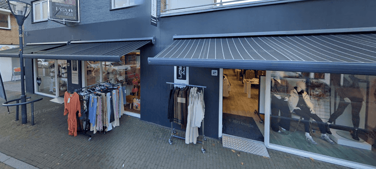 De winkelgevel van Label Trends Fashion & Bodywear met kledingrekken aan de straat in Denekamp